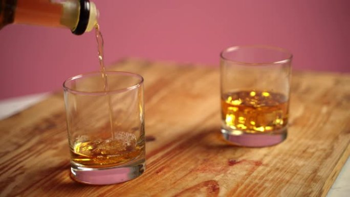 酒保将威士忌倒入玻璃杯中，然后在里面扔冰块。Vintagebar柜台，水晶眼镜配古老的棕色酒精饮料。