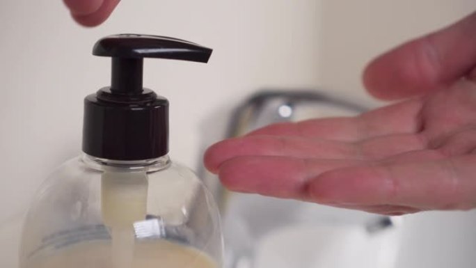 手按压分配器并取一部分液体肥皂对手进行消毒