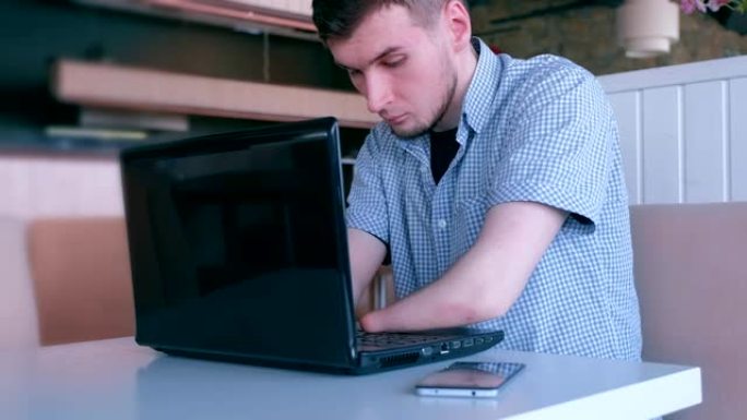 一个被截肢的年轻人在咖啡馆用笔记本电脑打字。