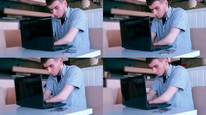 一个被截肢的年轻人在咖啡馆用笔记本电脑打字。