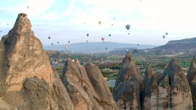 彩色热气球飞越卡帕多细亚山谷和砂岩的真菌形式的鸟瞰图，土耳其卡帕多细亚火山山上的无人机镜头