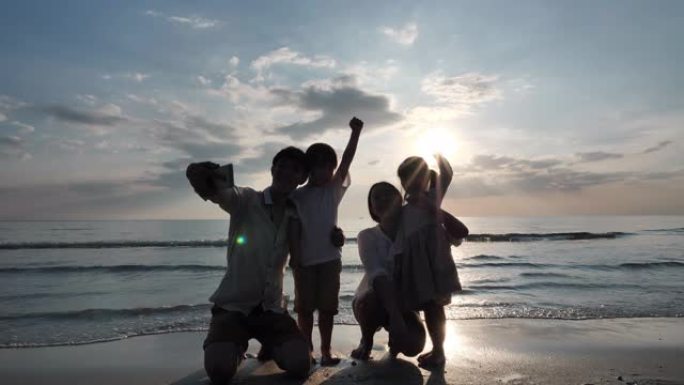 暑假快乐的亚洲家庭父亲在海滩上用智能手机拍摄全家福。放松假期和旅行理念。慢动作