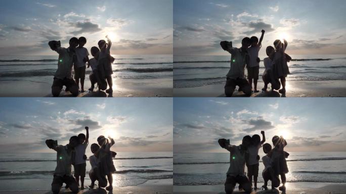 暑假快乐的亚洲家庭父亲在海滩上用智能手机拍摄全家福。放松假期和旅行理念。慢动作