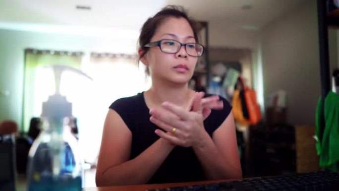 亚洲妇女消毒她的手消毒在家庭办公室。