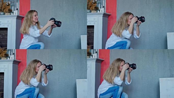 美丽的女孩摄影师瞄准框架，将相机握在手中。女孩在工作室拍照，她很高兴。