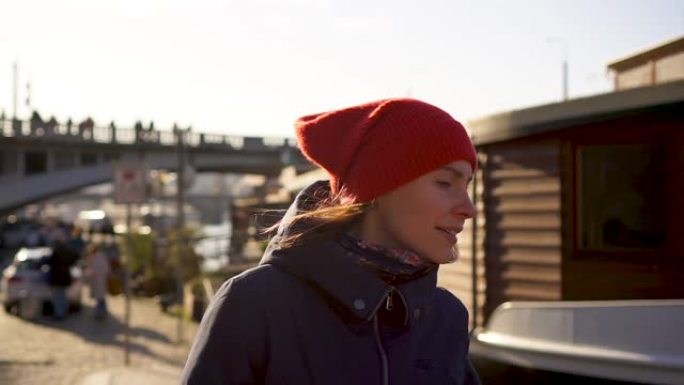 戴着红帽子的年轻女子行走布拉格海滨长廊桥船阳光明媚的背景