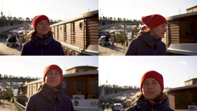 戴着红帽子的年轻女子行走布拉格海滨长廊桥船阳光明媚的背景
