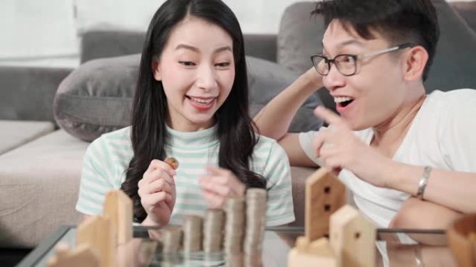 年轻迷人的亚洲男女夫妇专注于集中资金储蓄和投资关注家庭金融理念概念手计数硬币堆堆栈和房屋模型