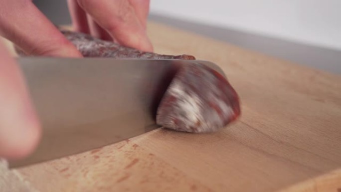 年轻人将西班牙传统自制的choriso香肠切成小块放在木制切菜板上