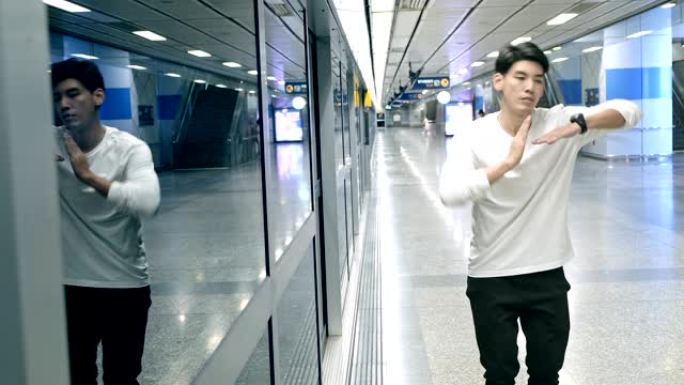 年轻人在地铁站做自由式街舞，机器人舞的中等镜头。亚洲男人。