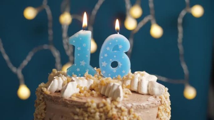 蓝色背景上有16号蜡烛的生日蛋糕。蜡烛吹灭了。慢动作和特写视图