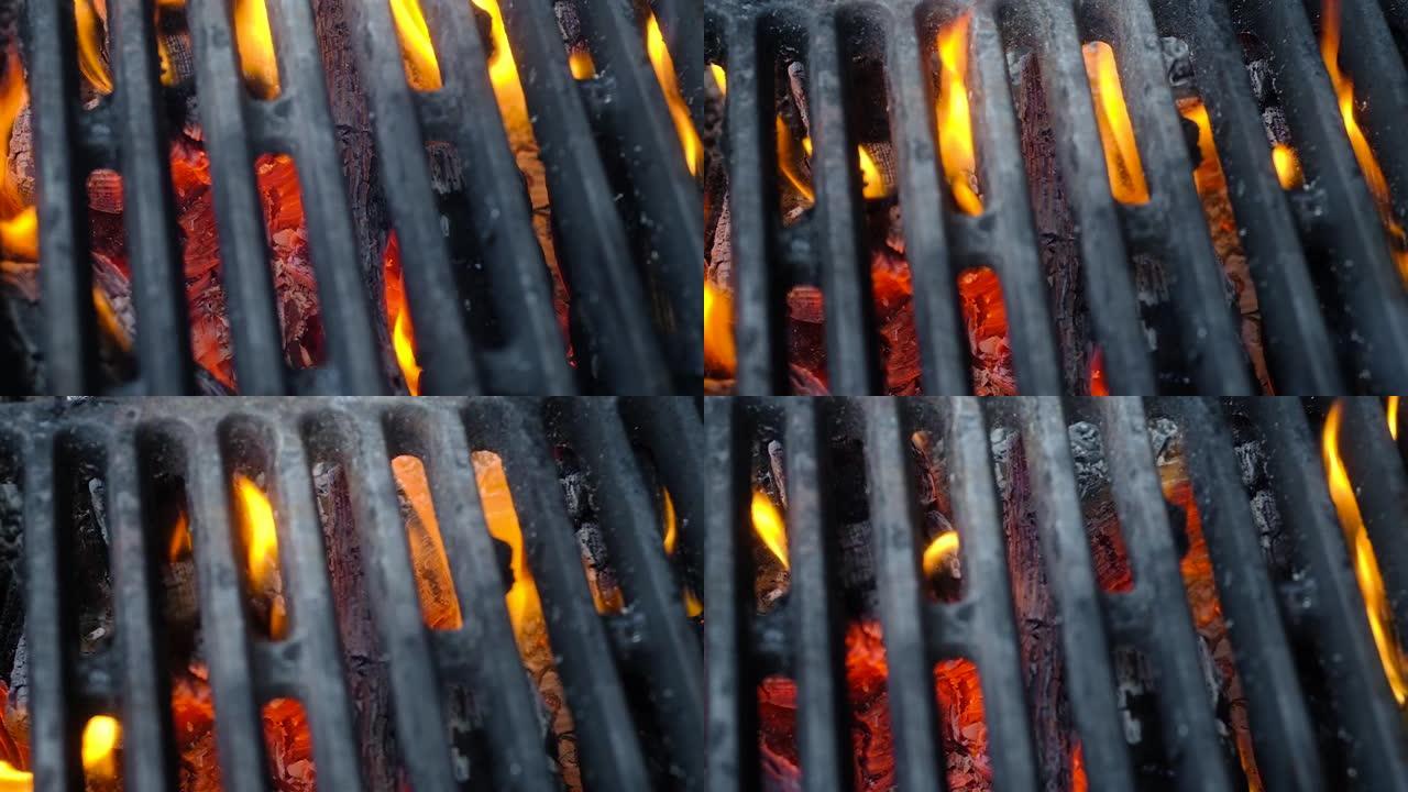 用粗铁条做的滚烫的灰色烧烤架躺在煤上。火焰从铁条中喷出。特写,俯视图。