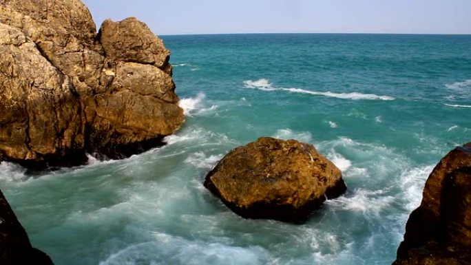 蓝色的海洋海浪坠入岩石。阳光明媚的夏日海浪景观