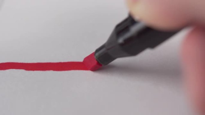 年轻人的手用毡尖笔在白纸上画出一条水平的鲜红色线