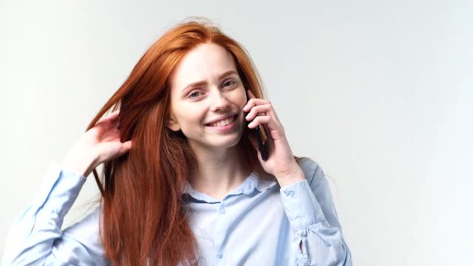 工作室里年轻的红头发女孩在智能手机上聊天的肖像