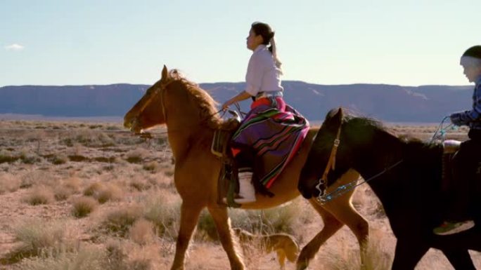 年轻的纳瓦霍兄弟姐妹骑着马，背景是纪念碑谷