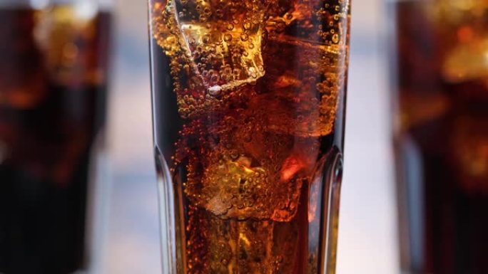玻璃中有可乐和冰块的特写气泡。碳酸饮料的气泡上升