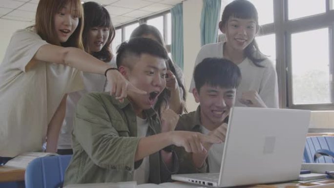 兴奋的大学生在教室里看着笔记本电脑
