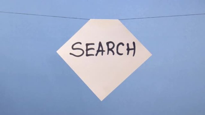 一名男子在蓝色背景上悬挂一张带有黑色铭文 “搜索” 的白纸