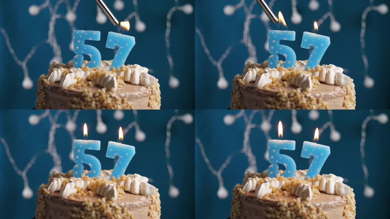 蓝色背景上有57号蜡烛的生日蛋糕。蜡烛着火了。慢动作和特写视图