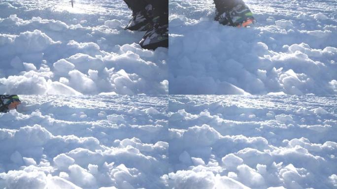 带有冰爪的山靴和带有背光太阳光束的雪地绑腿的特写镜头。高高的登山者在坚硬的雪中猛击靴子，登上山顶。