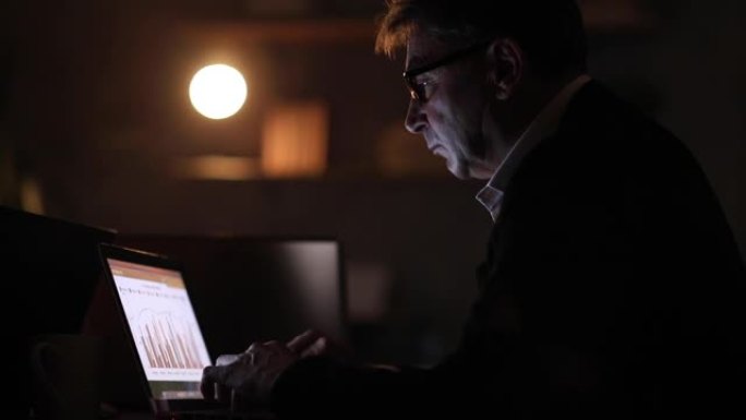 疲倦的男人在办公室深夜使用笔记本电脑