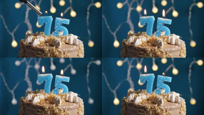 蓝色背景上有75号蜡烛的生日蛋糕。蜡烛着火了。慢动作和特写视图