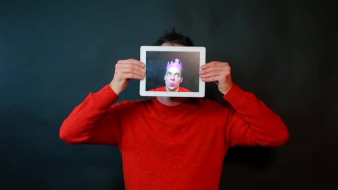 平板电脑屏幕上一个人的肖像。这个人做鬼脸，环顾四周。