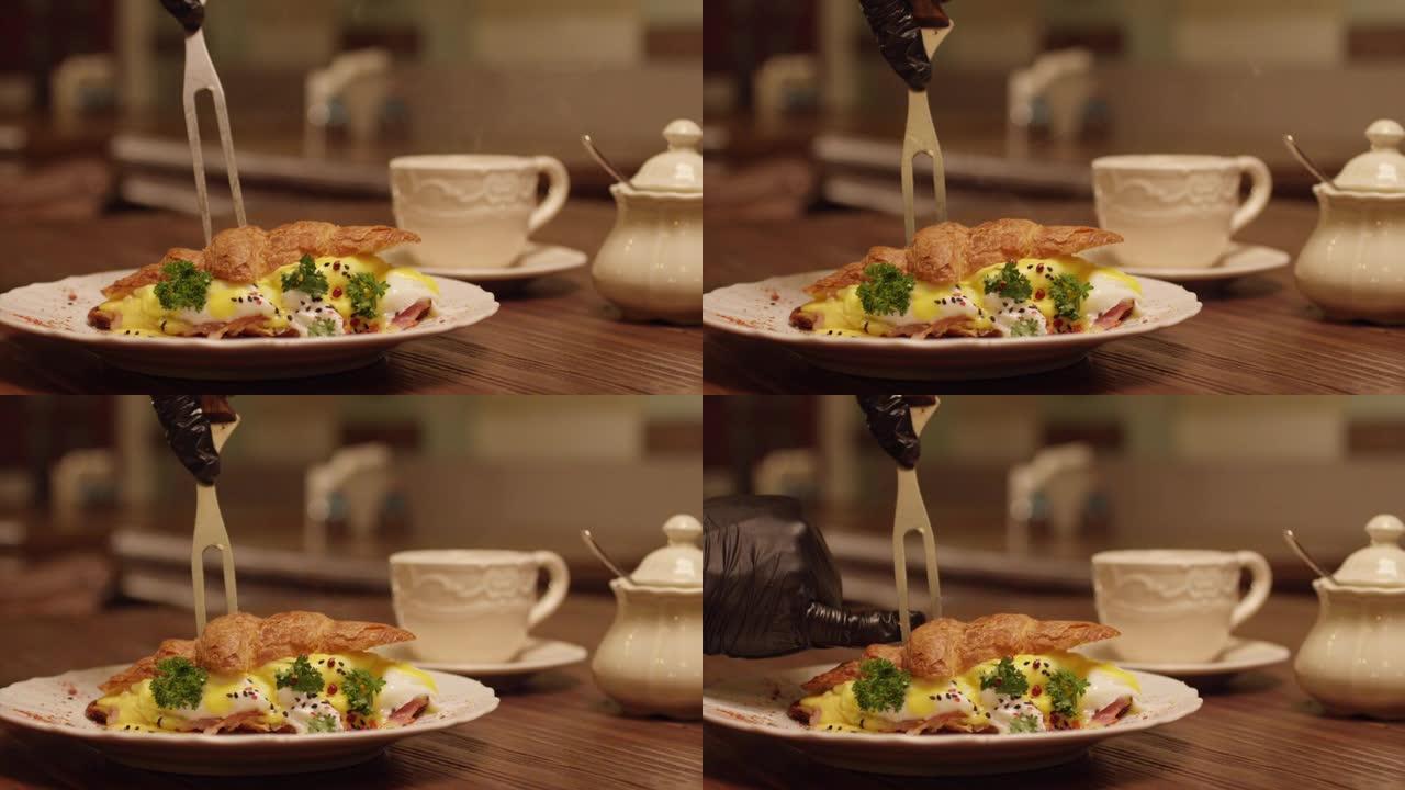 将羊角面包中的蛋汁倒入盘子中的慢动作。专业厨师用叉子切成羊角面包煎蛋卷。餐厅内餐桌上的早餐。在红色史