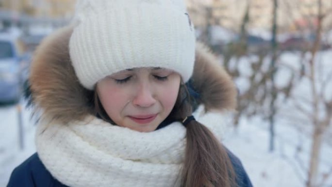 肖像让年轻女孩在冬天的街道上哭泣。特写脸不快乐的女孩在雪城街上冬天散步时哭泣。