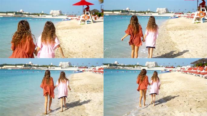 小快乐有趣的女孩在热带海滩一起玩有很多乐趣。晴天，海里有雨