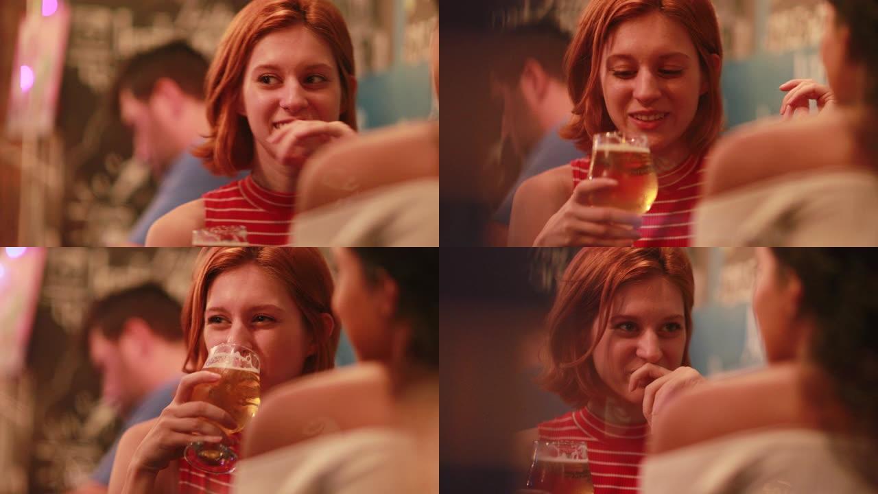 坦率的年轻红发女人晚上喝啤酒和朋友说话