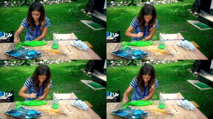 年轻艺术家女人在院子里的木桌上画鱼装饰