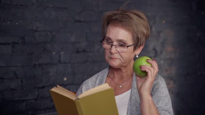 中年妇女在家吃苹果看书
