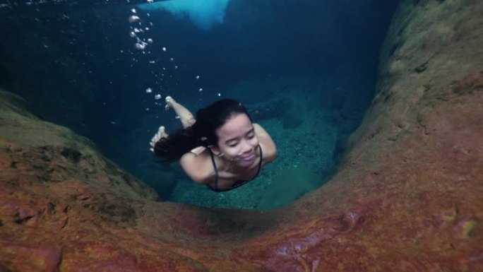 水下射击: 一名年轻女子在干净的自然游泳池水下游泳。
