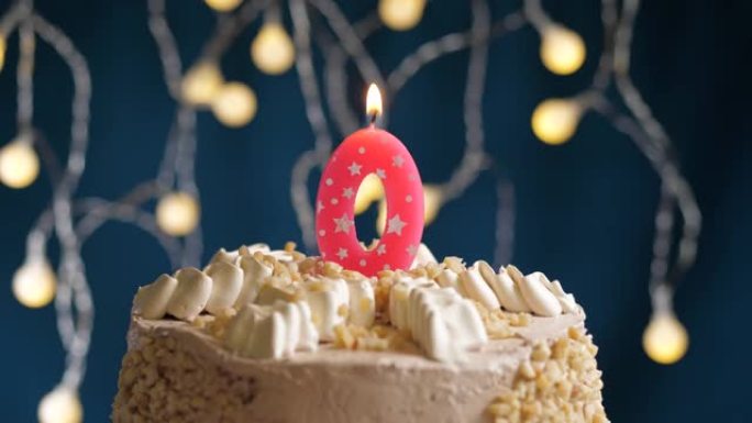 蓝色背景上有0号粉色蜡烛的生日蛋糕。蜡烛吹灭了。慢动作和特写视图