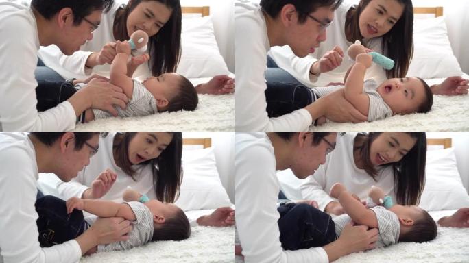 年轻的亚洲父亲家庭与妻子温柔地亲吻他的男婴。男人和女人享受与孩子在一起的时光