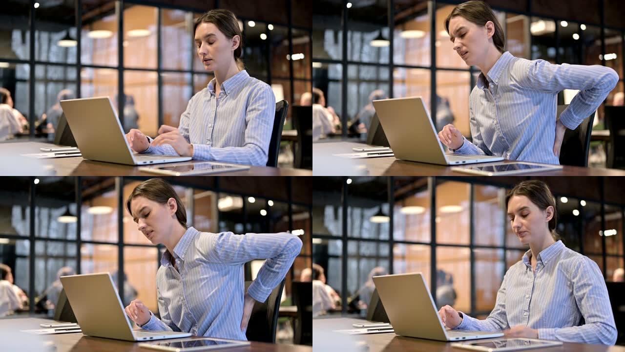 患有脊椎背痛的女人在笔记本电脑上工作