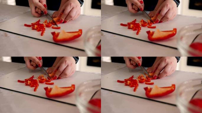 母亲和小女儿的特写镜头，将新鲜的红甜椒切成丁。