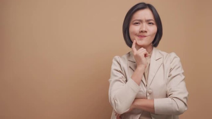 快乐的商业亚洲女人有一个好主意交叉双臂站在米色背景上孤立的复制空间。4k视频