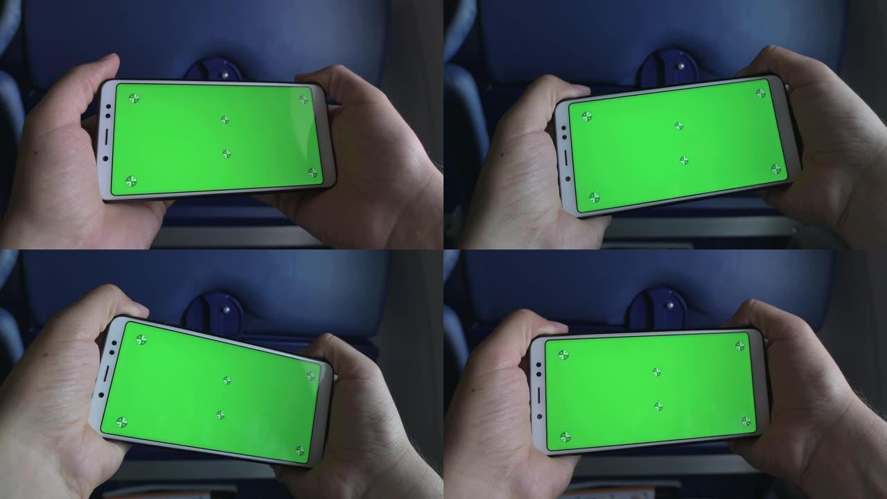 一个智能手机的特写镜头，一个飞机机舱里的家伙手里有一个绿屏。旋转和倾斜屏幕。