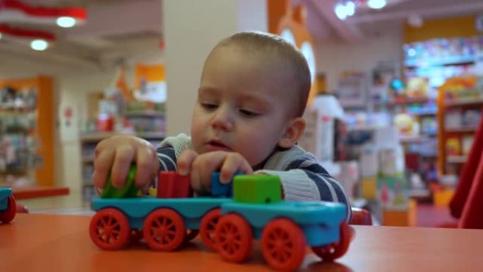 可爱的专注男婴在商店里学习玩幼儿玩具。特写肖像镜头。