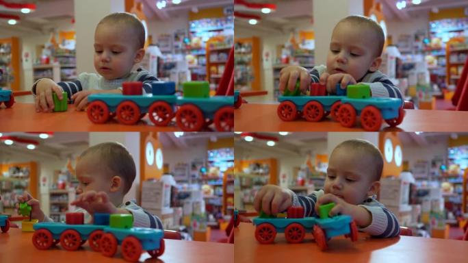 可爱的专注男婴在商店里学习玩幼儿玩具。特写肖像镜头。