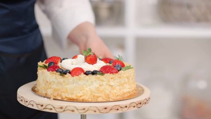 女厨师双手将草莓添加到盘子上旋转的蛋糕中。在4k红色相机上近距离拍摄