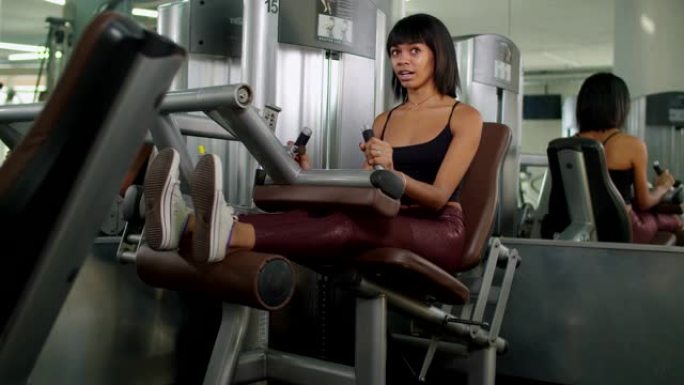女人在健身房用伸腿机锻炼