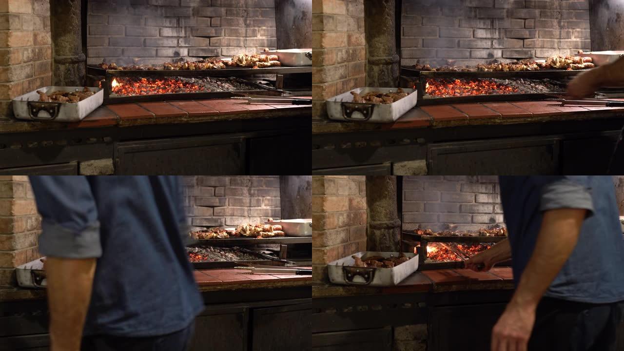 专业的男厨师在古老的传统意大利餐厅的砖制自制炉子的烧烤炉上烤肉片。男子在篝火上煮五香火腿，牛肉，猪肉