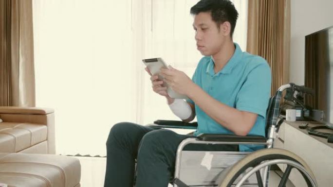 东南亚残疾人坐在轮椅上在家通过平板电脑查看电子邮件