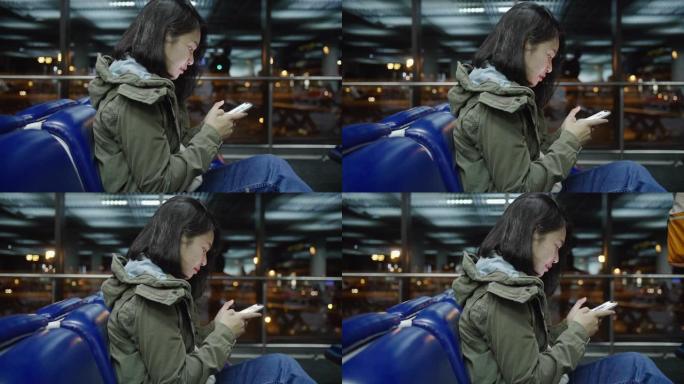 晚上，女乘客触摸并使用智能手机在出发航站楼机场等待航班。