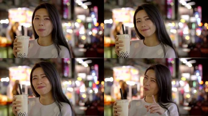 亚洲女子在夜市享用带街头食品的珍珠奶茶