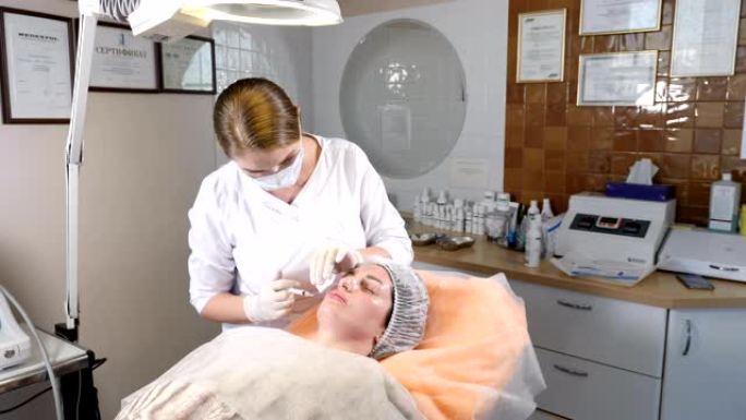 美容诊所。戴着手套的美容师在女性皮肤中进行面部老化注射。女人接受美容面部美容程序。肉毒杆菌。胶原蛋白